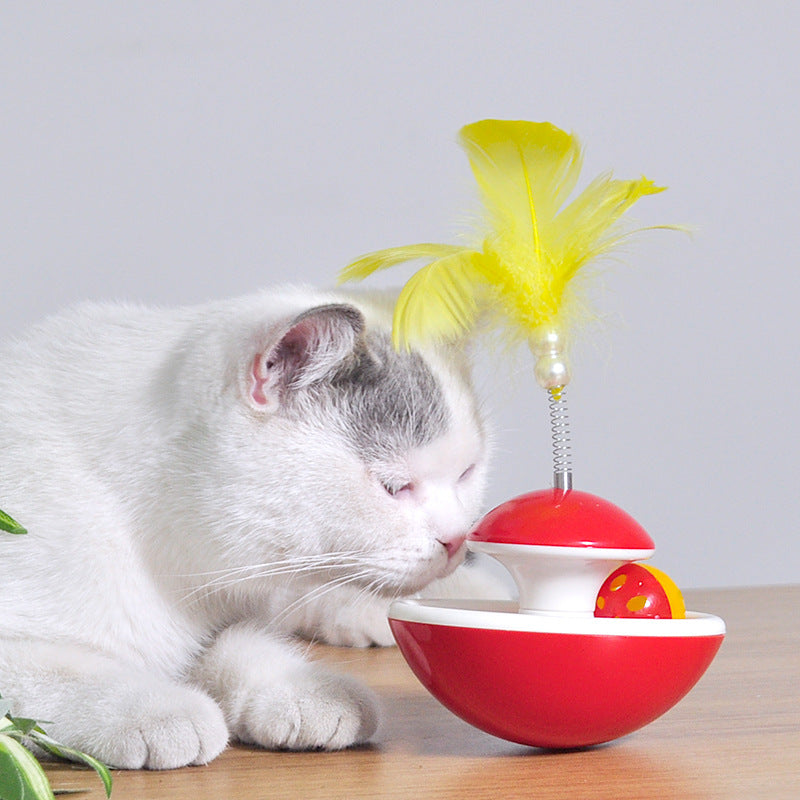 Red tumbler cat toy with yellow feathers on a spring and a yellow ball with holes in its white rim