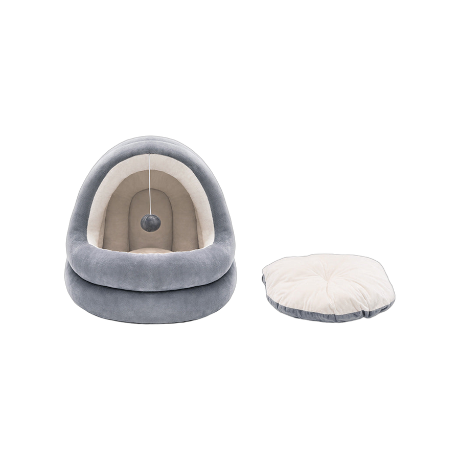 Grey hooded cat bed with cream lining and a hanging pompom ball, beside its removable cream cushion, front view